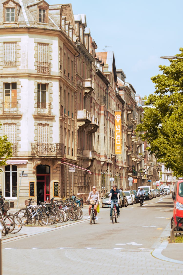 Man And Woman Biking On The Road Beside The Buildings 