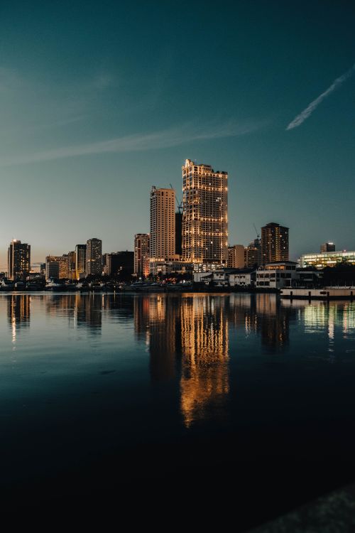 Free Stunning view of Manila's skyline at night with buildings reflecting on the calm river. Stock Photo