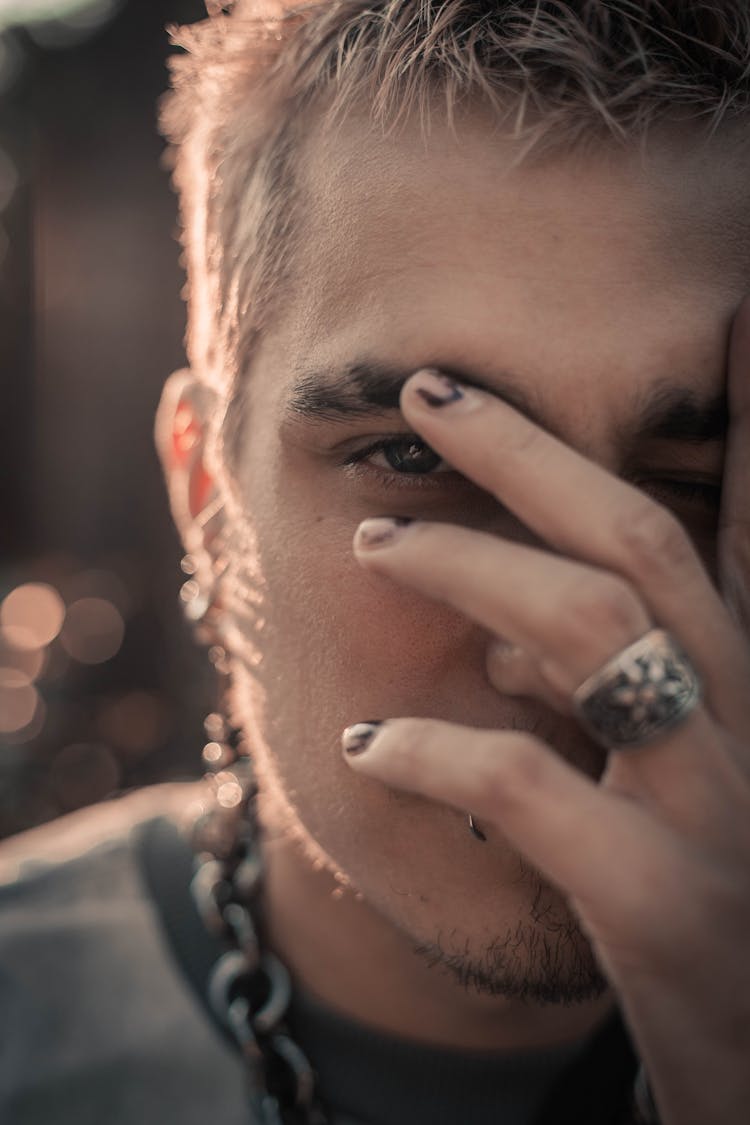 A Man Partially Covering His Face With His Had 