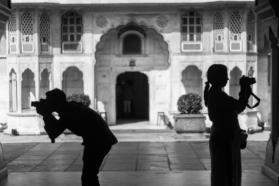 Silhouettes of photographers capturing images in a historic Jaipur courtyard.