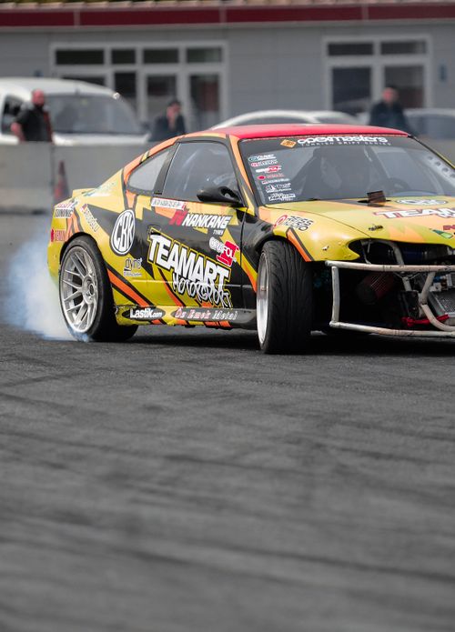 Free A vibrant drift racing car skids on asphalt, creating smoke. Stock Photo