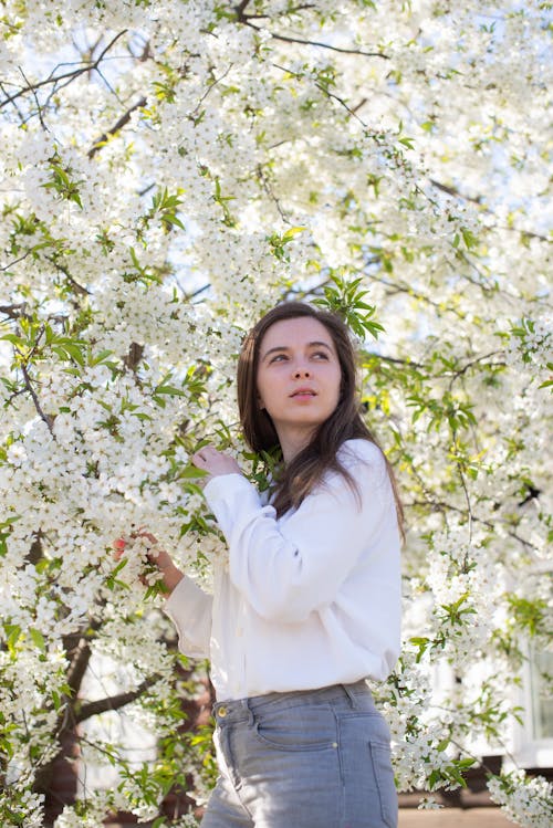Young Woman Standing on the Background of Flowering Trees