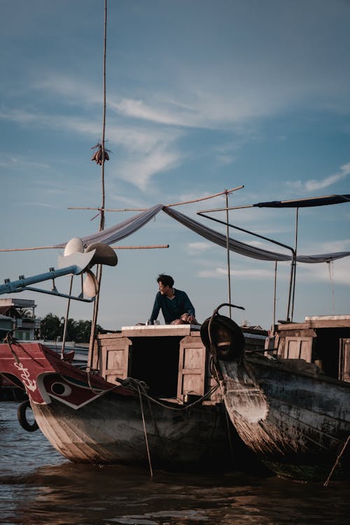 Man Sitting on a Fishing Boat in Harbor 
