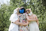 Three Girls with Ribbon in Hair Standing Together in Garden