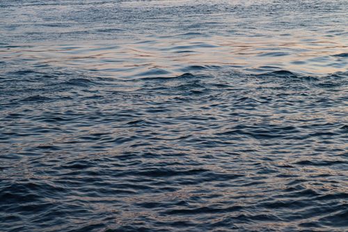 Free Serene ocean waves gently rippling at sunset, capturing golden hour's peaceful ambiance. Stock Photo