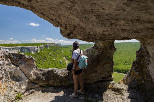 Free Woman hiking through rugged cliffs with breathtaking views of lush green valleys. Stock Photo