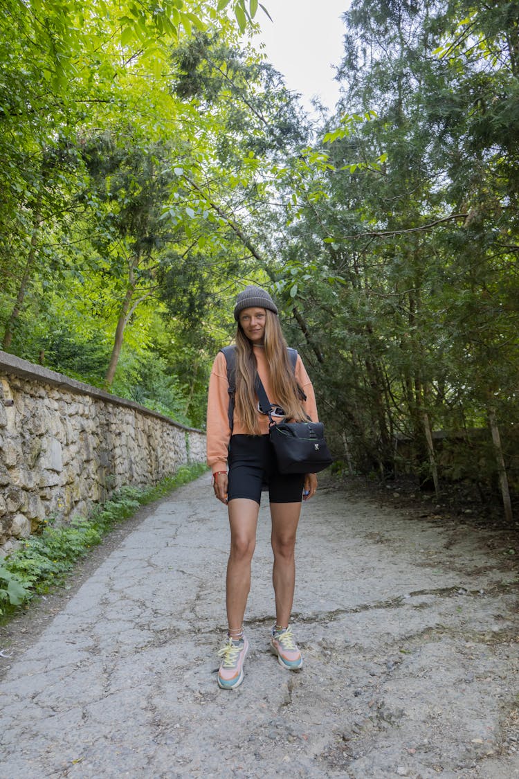 Woman In Sweater Nd Black Shorts Standing On Pathway