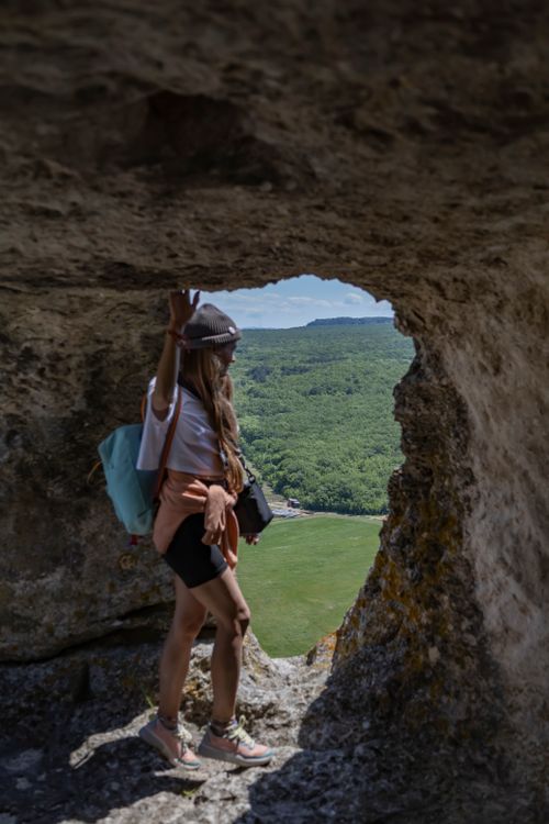 Free A woman explores a scenic landscape seen through a natural rock formation. Stock Photo