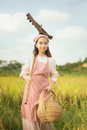 Young Girl Holding a Basket and Rake while Standing on a Field 