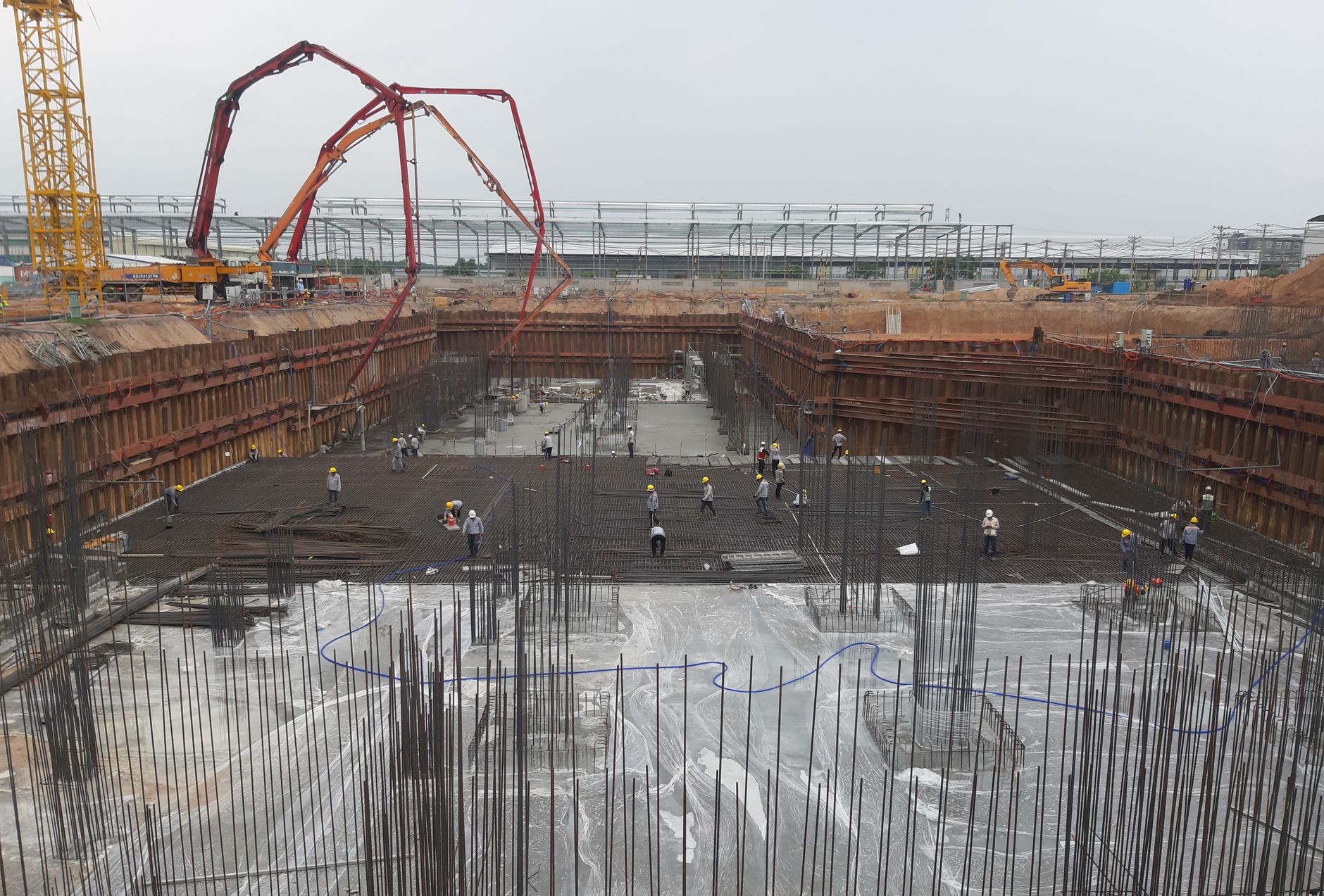 Construction site with workers setting foundation and steel reinforcements.