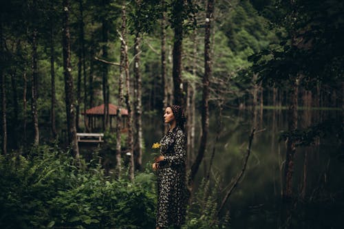 Woman in Black and White Floral Dress Standing in the Forest