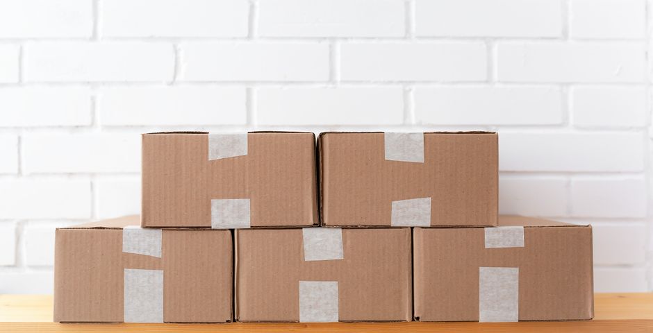 Taped cardboard cartons stacked on a shelf — egg cases are glued into flap creases where handling never reveals them