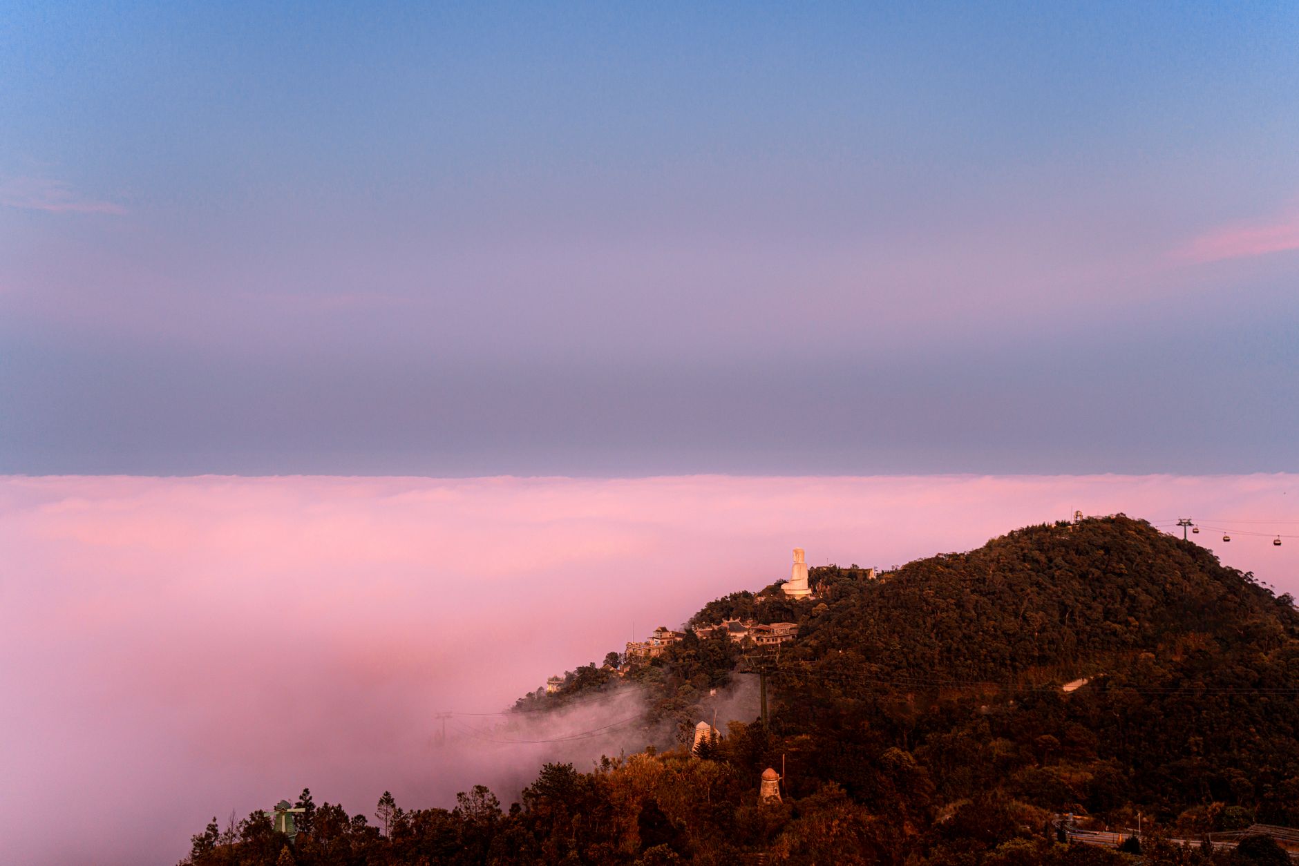A breathtaking view of Bà Nà Hills engulfed in soft clouds during sunset in Đà Nẵng, Vietnam.