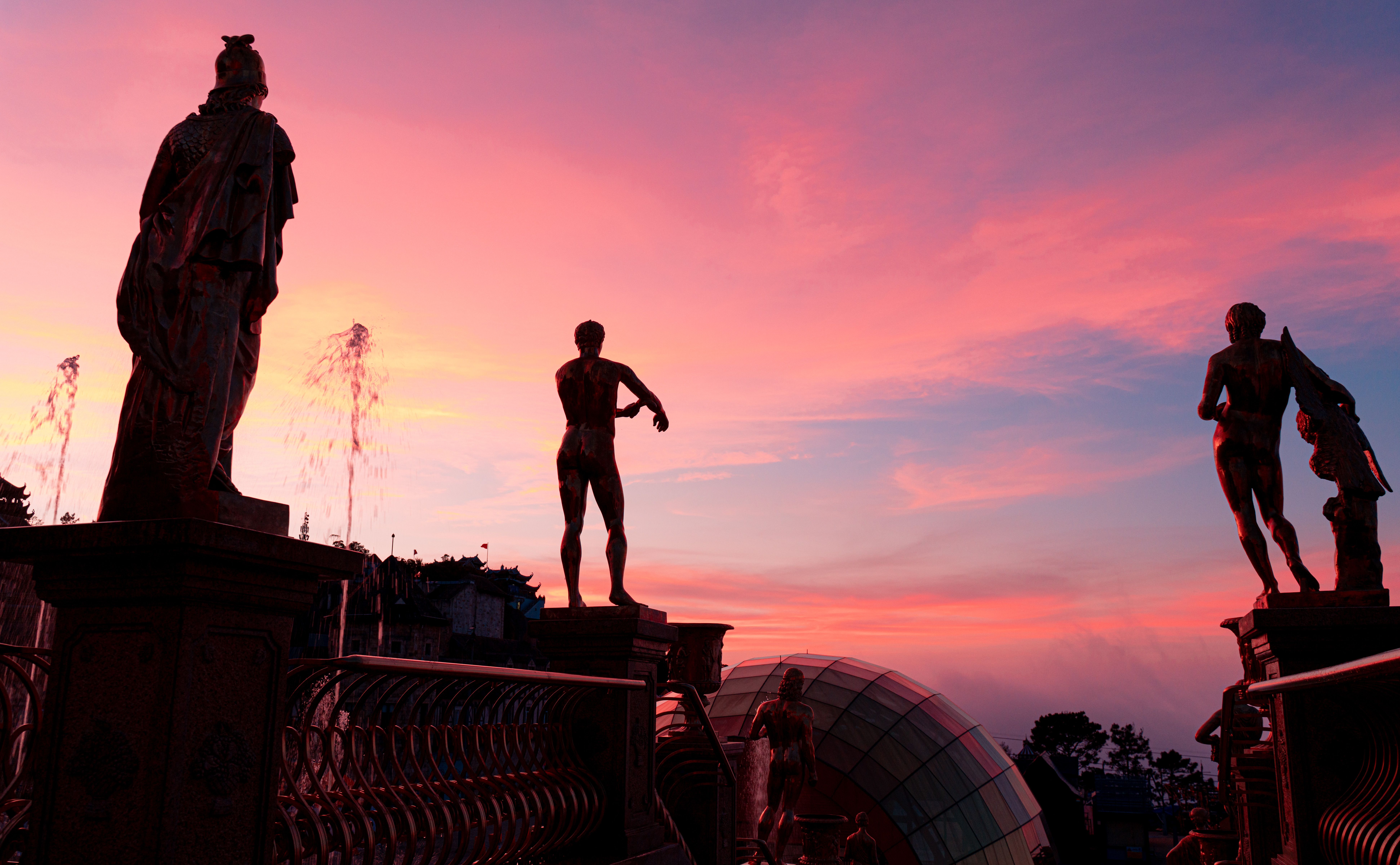 Majestic statue silhouettes against a vibrant sunset sky in Đà Nẵng, Vietnam.