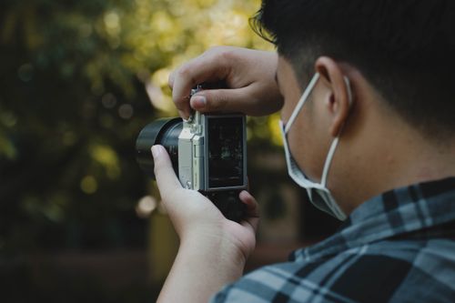Free A man capturing a nature scene outdoors in Vietnam, wearing a face mask. Stock Photo