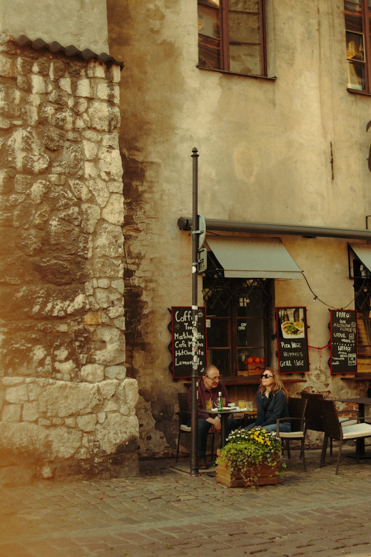 Two Adult People Sitting At Table In Outdoor Garden