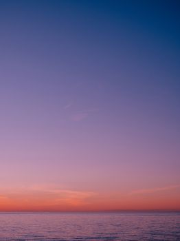 A tranquil ocean view at sunset with pink and purple skies, offering a peaceful seascape.