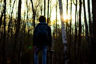 摄影师在秋天森林的日出背景下拿着相机