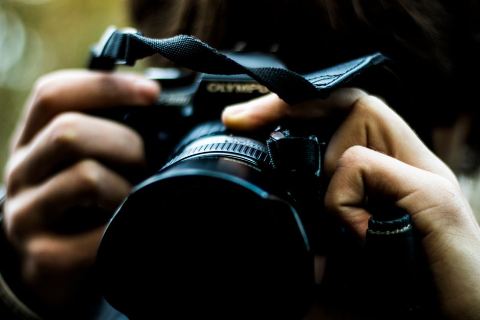 カメラを握る手の親密なショット。写真への情熱を強調しています。