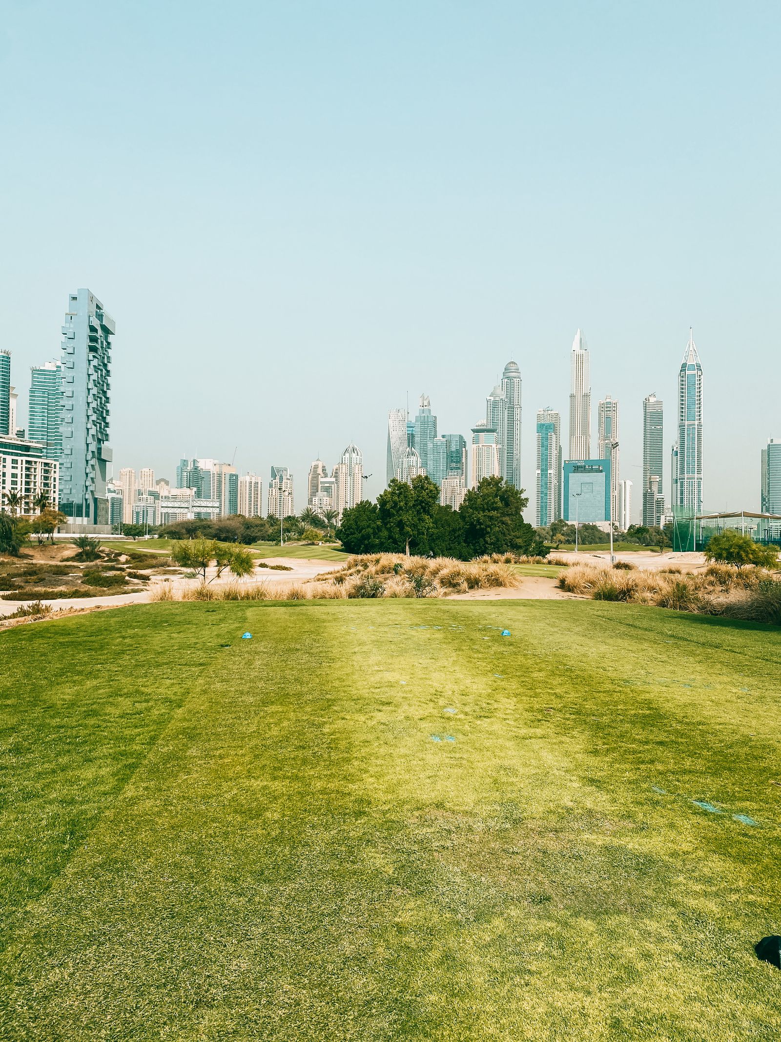Green golf fairway with the Dubai skyline behind, on the championship course bordering the community