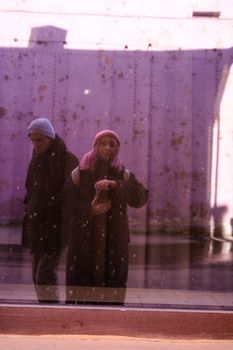 A vibrant reflection portrait featuring two individuals with colorful hair and hats.