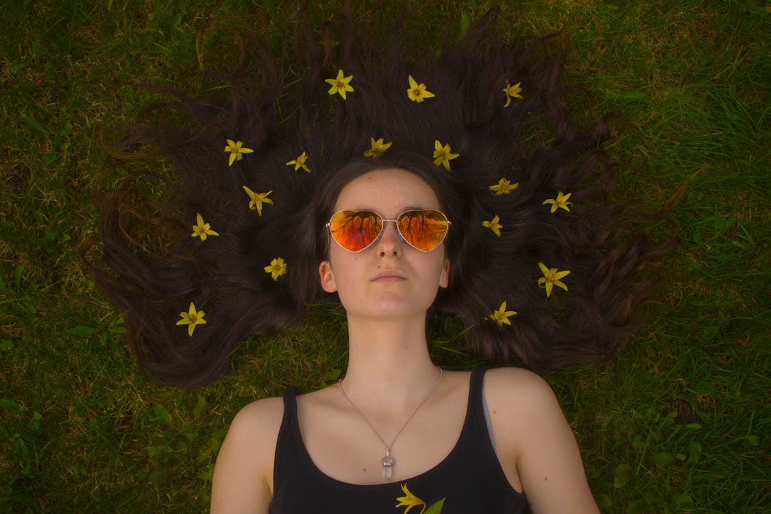 Woman Wearing Aviator Sunglasses Laying on Lawn Field