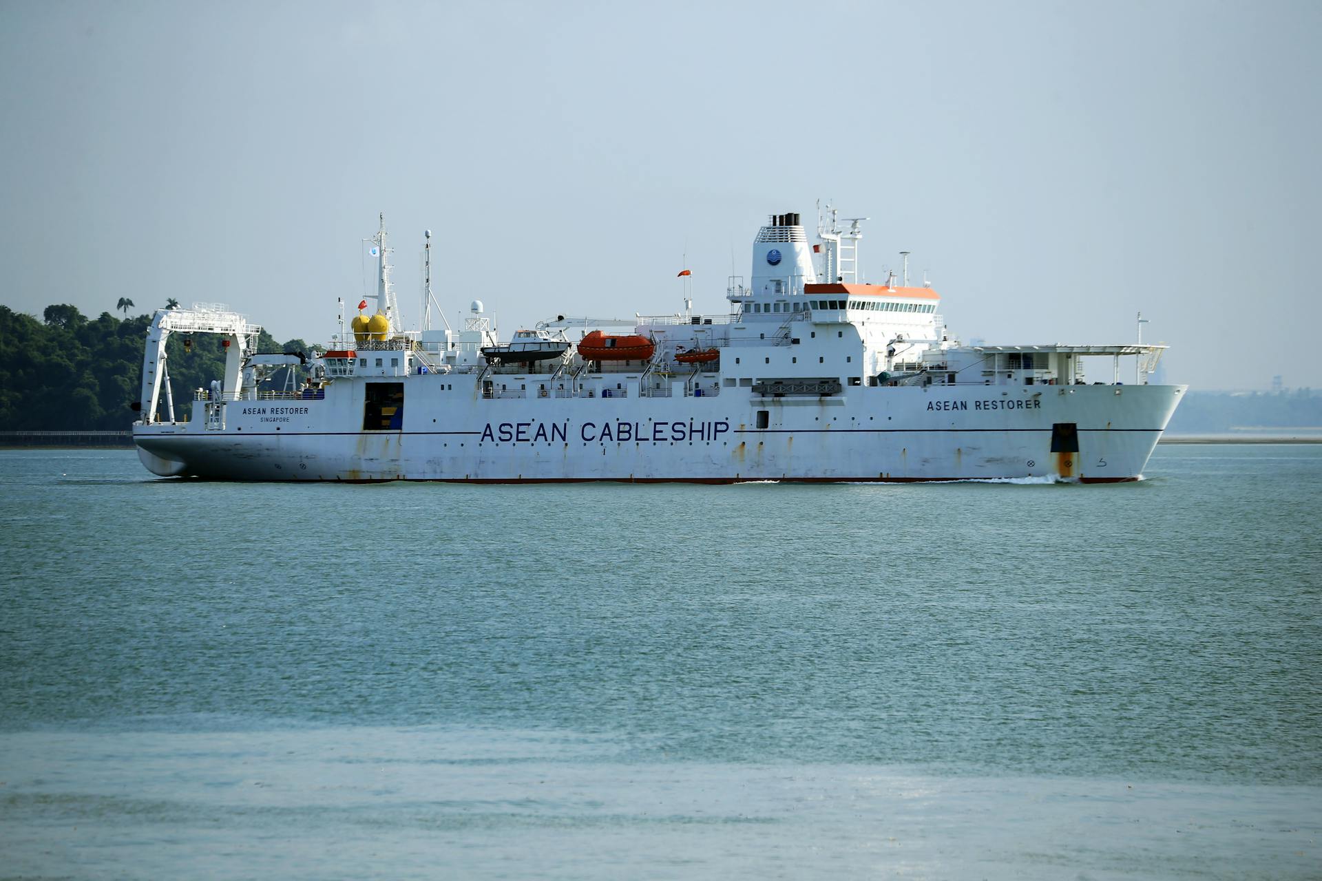 A cable ship named ASEAN Restorer navigating in clear ocean waters, highlighting maritime technology.