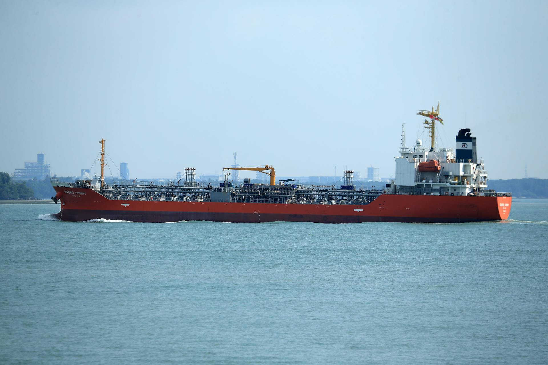 An oil tanker travels through a commercial harbor on a clear day.