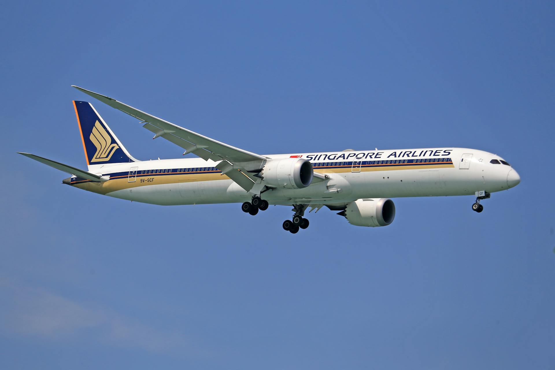 A Singapore Airlines Boeing 787 Dreamliner flying against a clear blue sky.