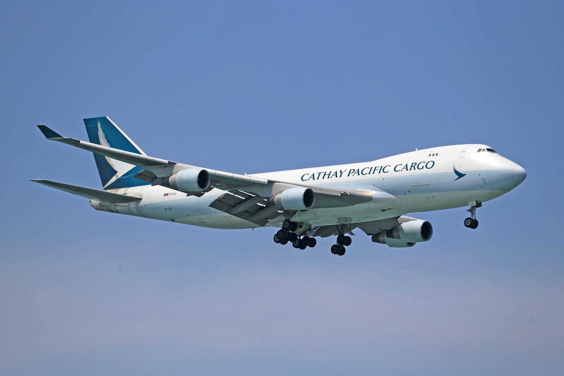 Cathay Pacific cargo plane flying against a clear blue sky.