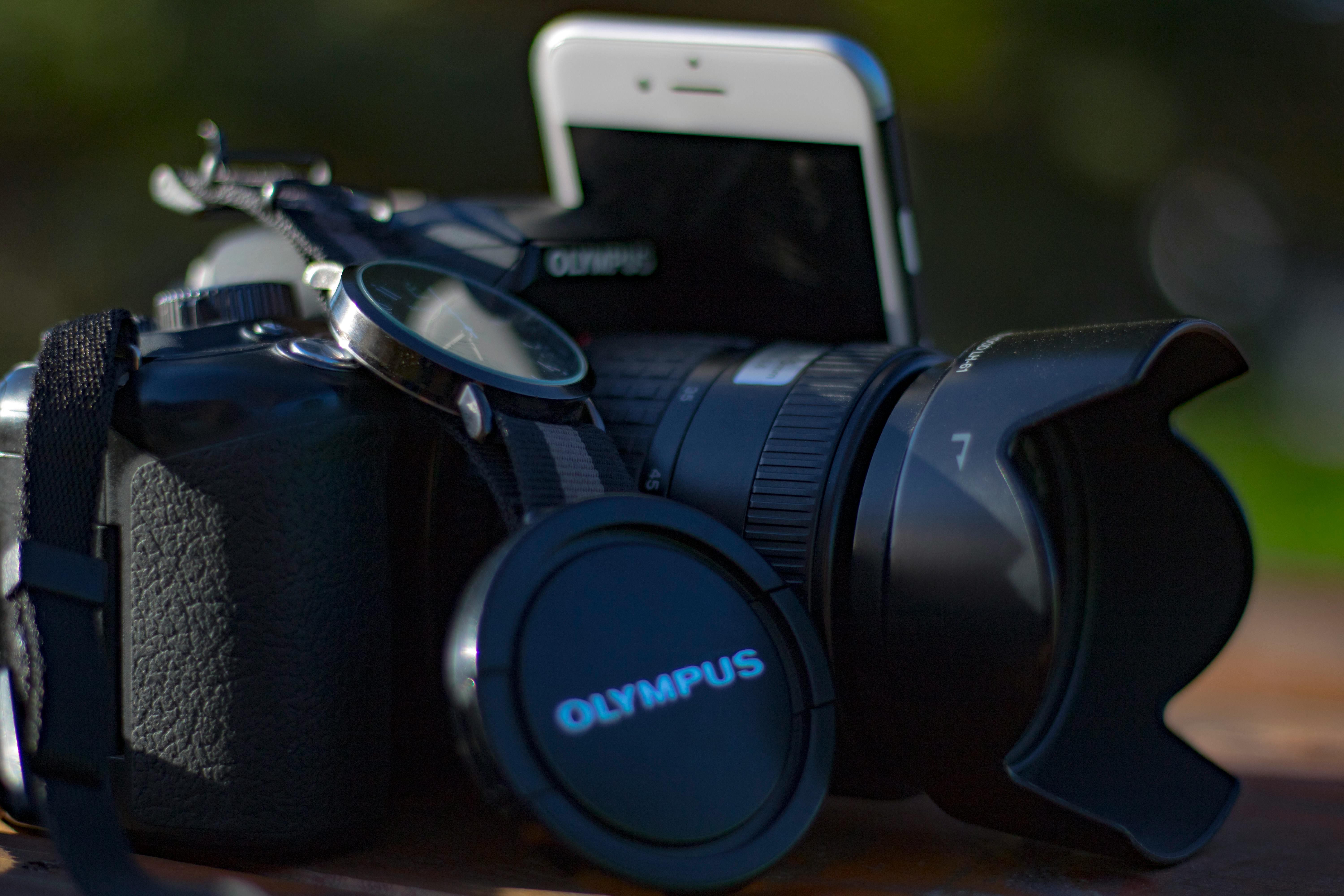 Black Olympus Dslr Camera Beside Silver Iphone 6