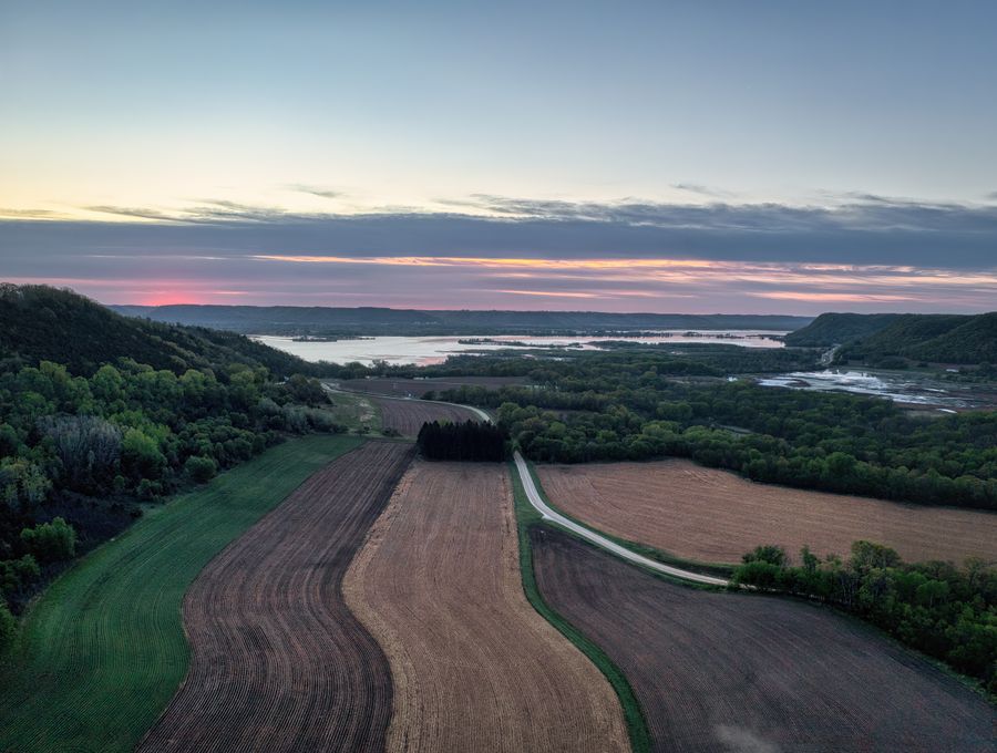 Aerial view of a river valley with fields and woodland at dusk — photo by Tom Fisk on Pexels