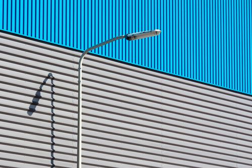 Free Minimalist urban scene with a lamppost casting a shadow on a striped building facade. Stock Photo