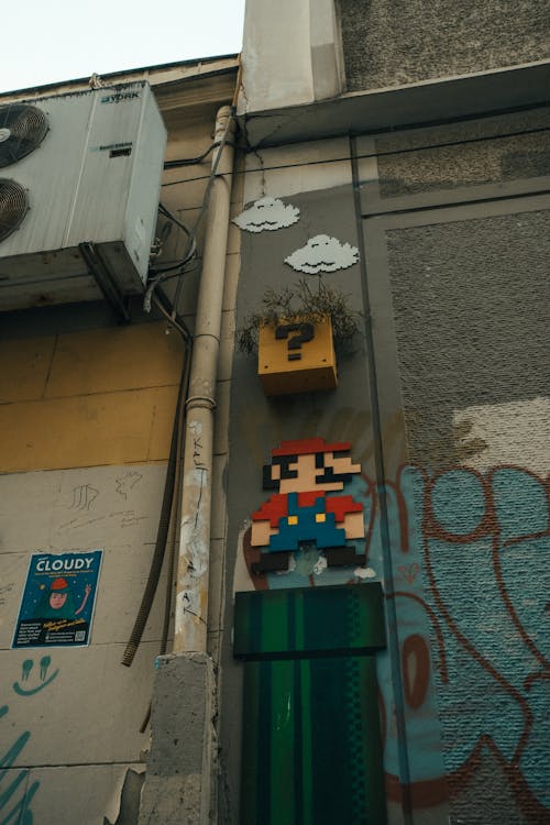 Photo of the Super Mario Graffiti, a Pipe and a Ventilator on a Building Wall