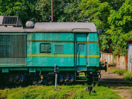 Free Vivid green train engine resting on railway tracks surrounded by lush greenery. Stock Photo