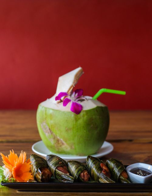 Free Green coconut drink and Thai cuisine with pandan chicken on wooden table. Stock Photo
