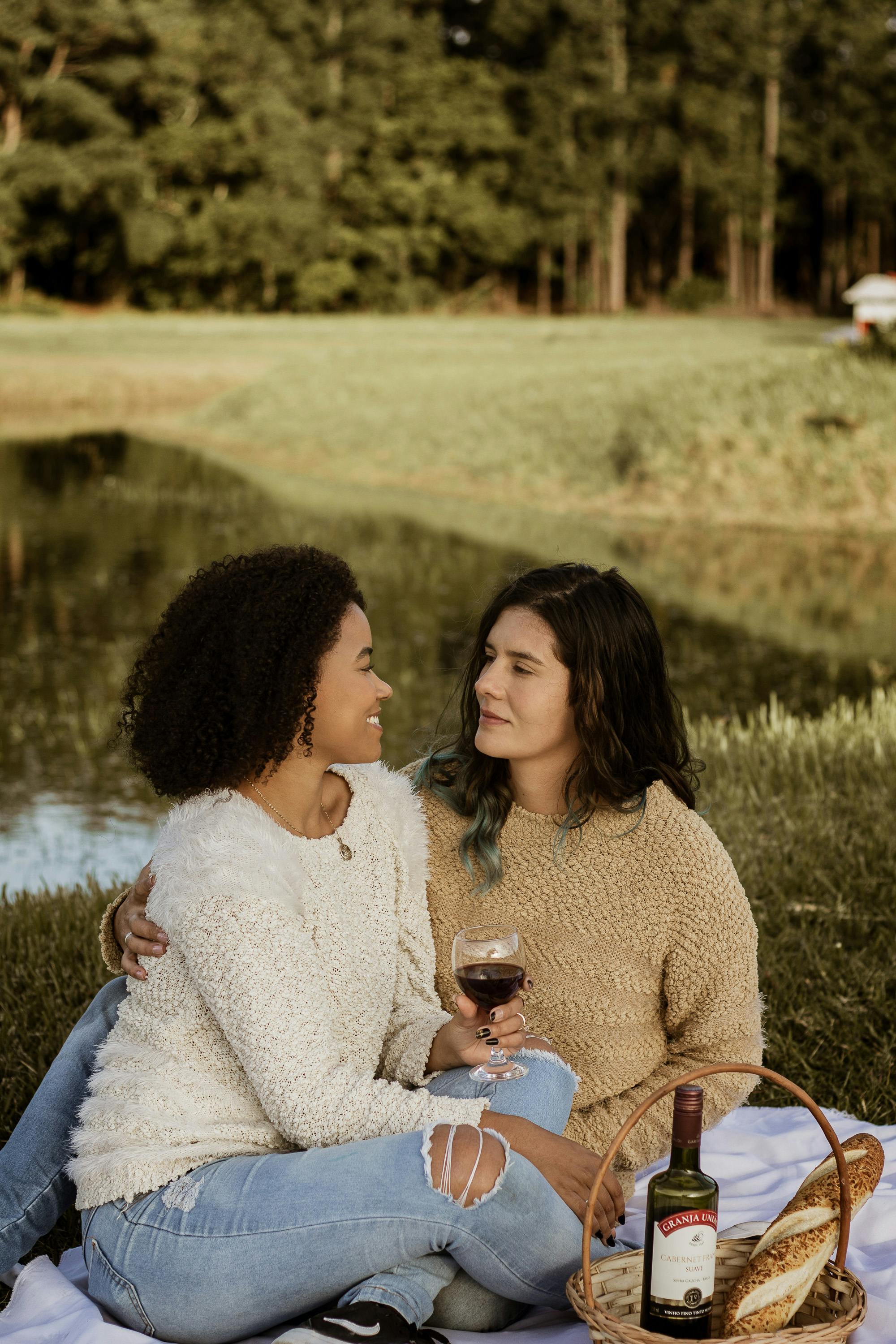 women sitting on a white picnic blanket facing each other