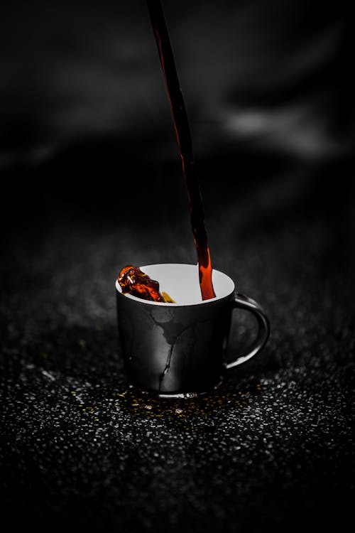 Free Brown Liquid Pouring on Black and White Ceramic Mug Selective Color Photography Stock Photo