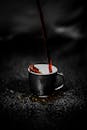 热气腾腾的黑咖啡倒入黑色杯子，表面带着深色纹理，香气浓郁