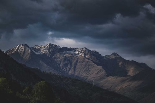 Free Dramatic mountain peaks under a dark, cloudy sky create a stunning landscape scene. Stock Photo