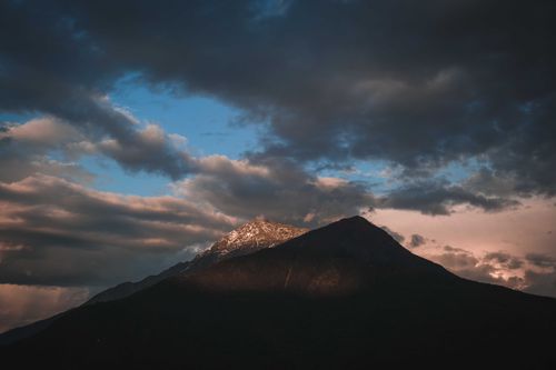 Free A stunning view of a mountain peak silhouetted against a dramatic cloudy sky. Stock Photo