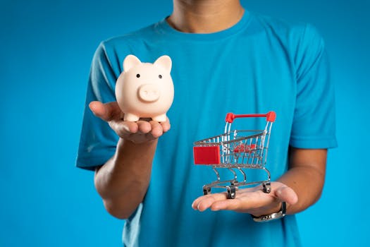 Man in blue shirt holding piggy bank and mini shopping cart, symbolizing savings versus spending.