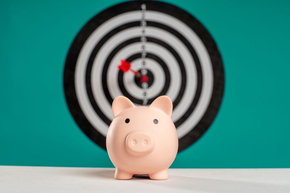 Free Piggy bank with bullseye dart board symbolizing financial goals and savings. Stock Photo