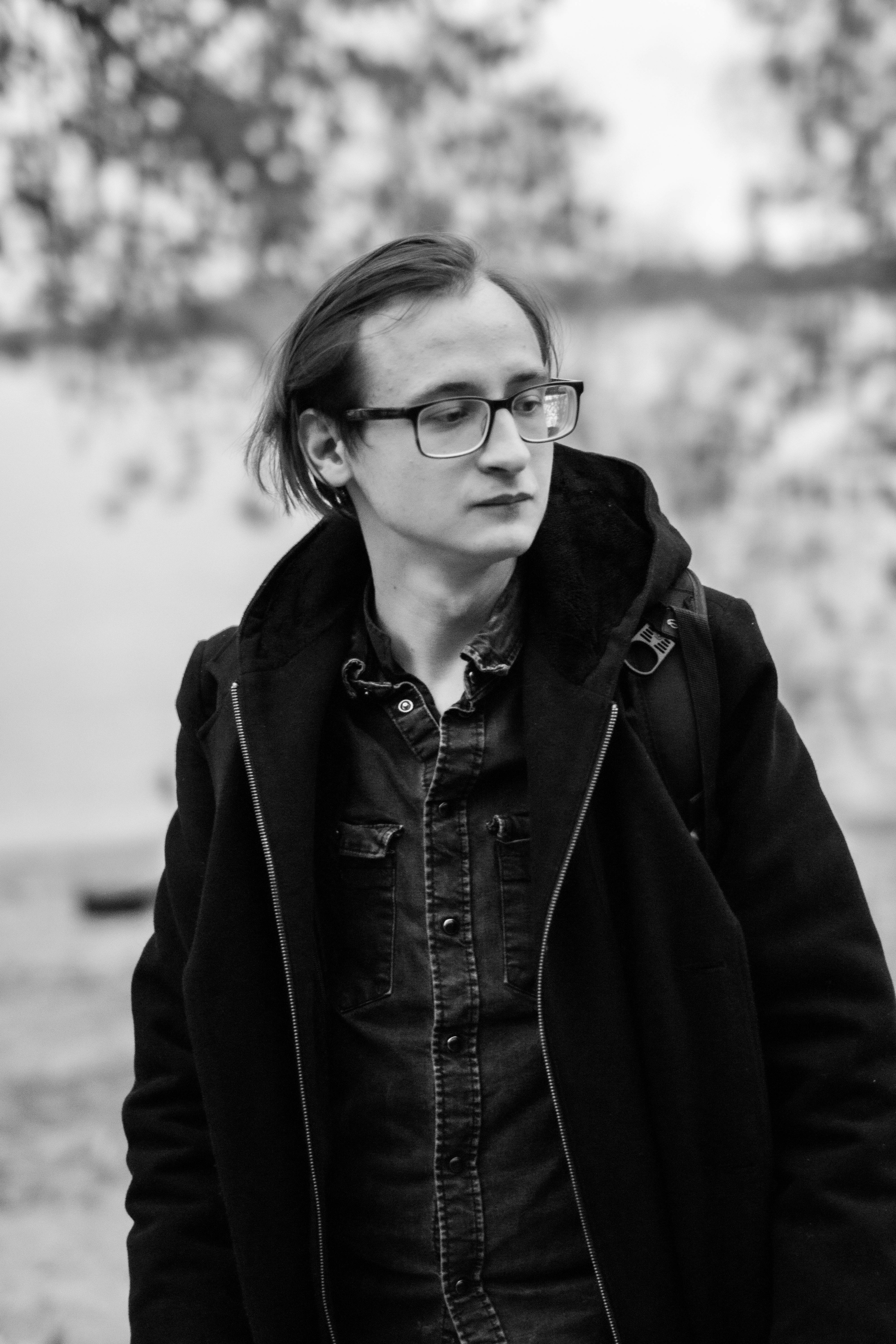 Stylish man with glasses in a black and white outdoor portrait.