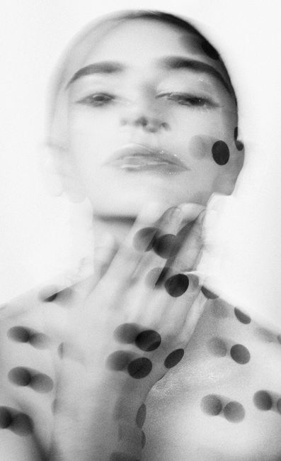 Abstract black and white portrait of a woman with blurred effect and black dots overlay.