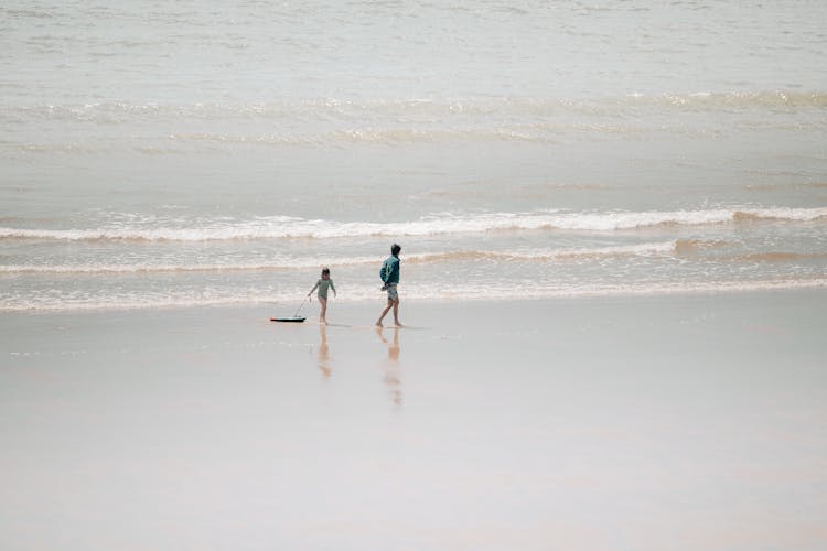 A Girl Pulling A Surfboard