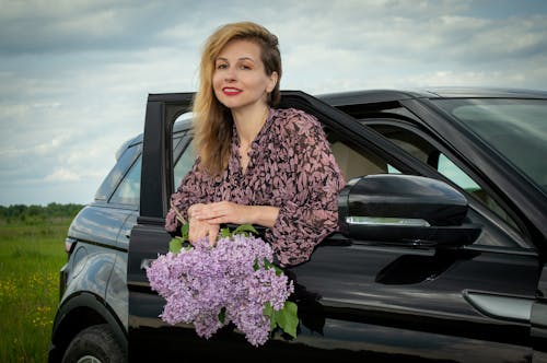 A Woman with Purple Flowers Posing in a Car