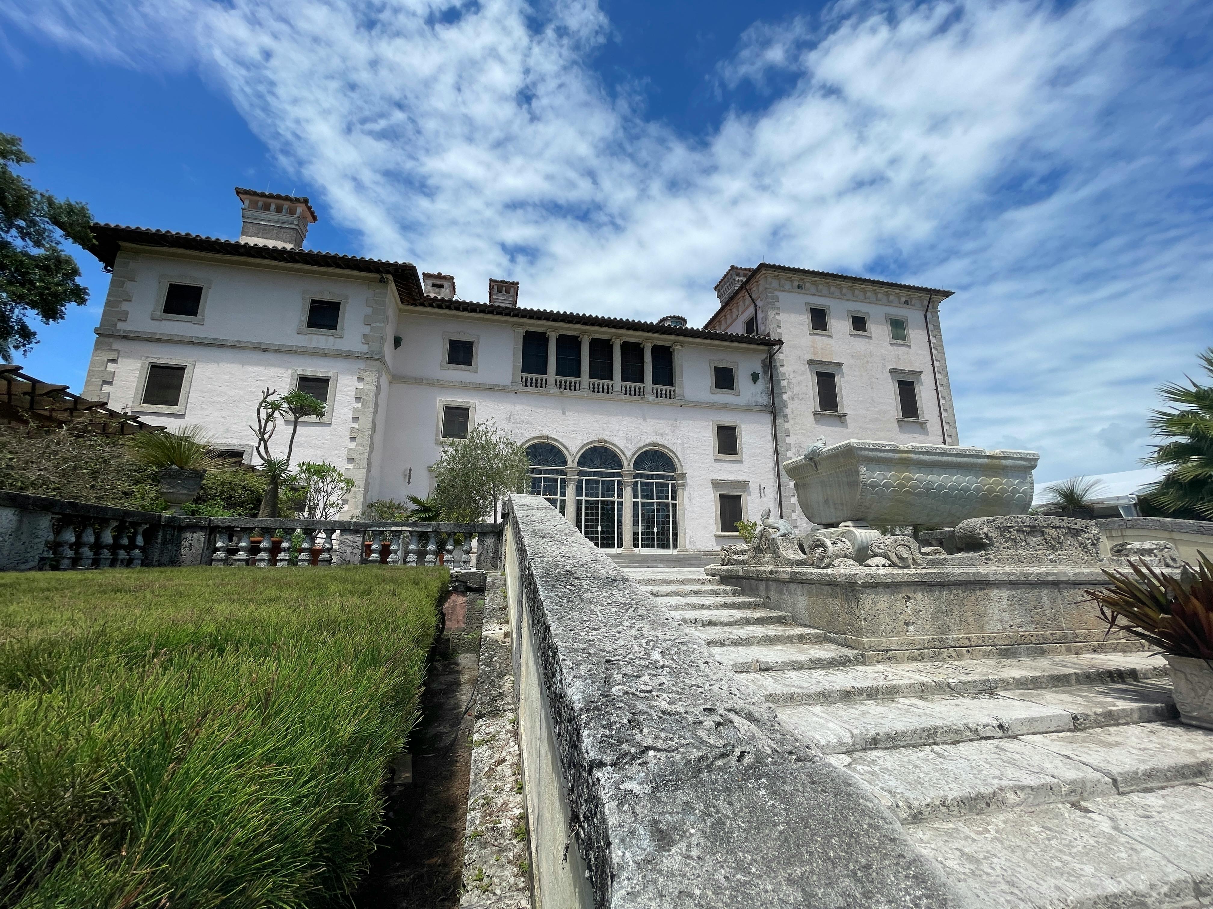 Free Beautiful facade of a historic mansion with a stunning stone fountain under a clear blue sky. Stock Photo