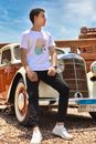 Man in White Crew Neck T-shirt and Black Pants Sitting on Red and White Vintage