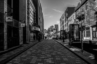 Grayscale Photo of Empty Street in Between Buildings